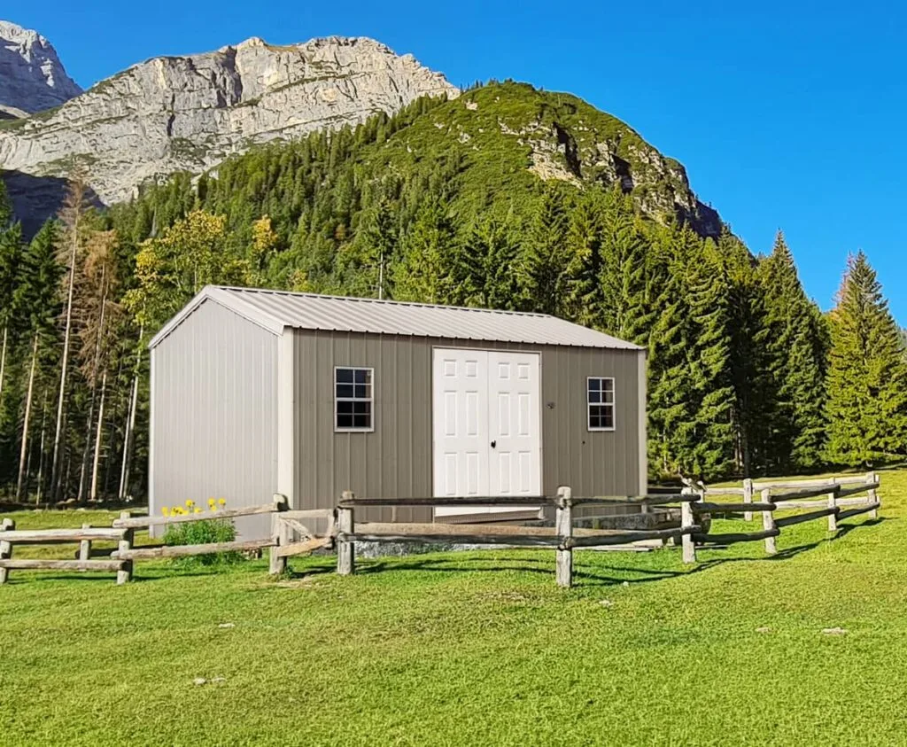 Tan Classic Garden Shed with white double doors and front windows in a mountain landscape