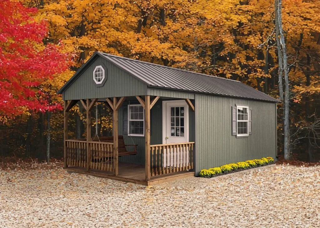Green Elite A-Frame Cabin with white trim, covered front porch, and octagon gable window in an autumn setting