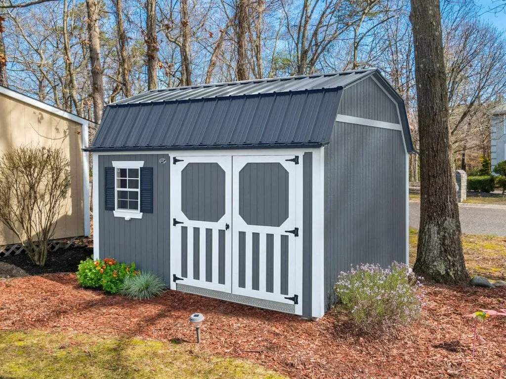 Gray Elite Lofted Garden Barn with white trim, double doors, and front window in a mulched yard
