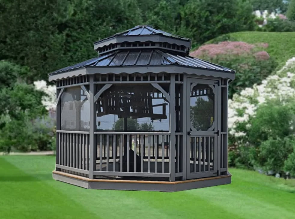 Gray screened gazebo with octagon shape, metal roof, and entry door in a landscaped lawn setting